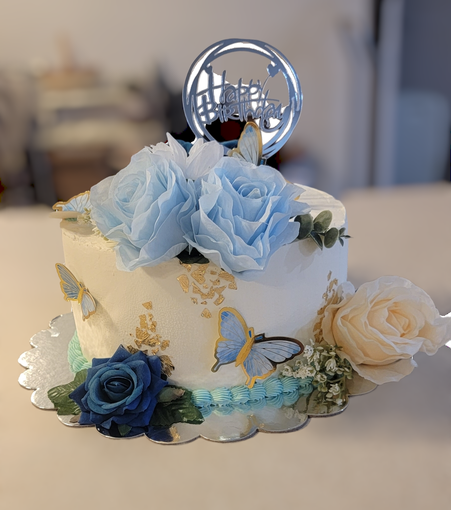 A white cake with blue flowers and butterflies