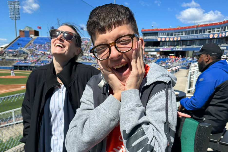 Hunter and his Direct Support Professional pose for the camera at a baseball game