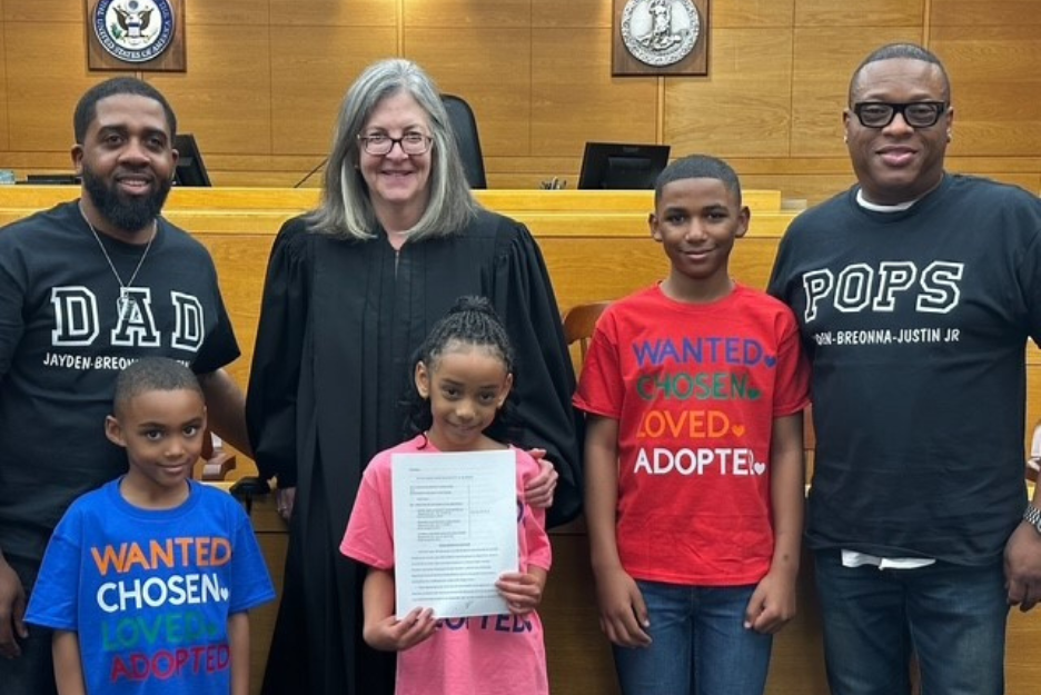 Wil, Justin, and their children smile with the family court judge
