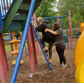 Abby helps a teacher climb a ladder on the playground