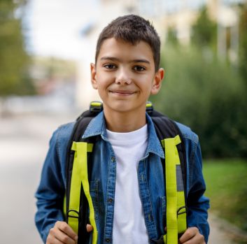 A Latino boy wearing a backpack smiles