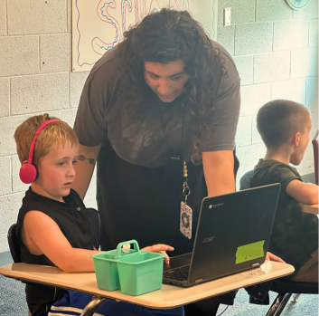 A teacher helps a student at his desk