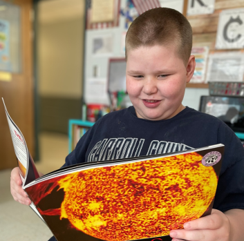 A student reads a book with a smile