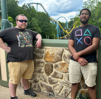 Brandon and Breon pose in front of a roller coaster