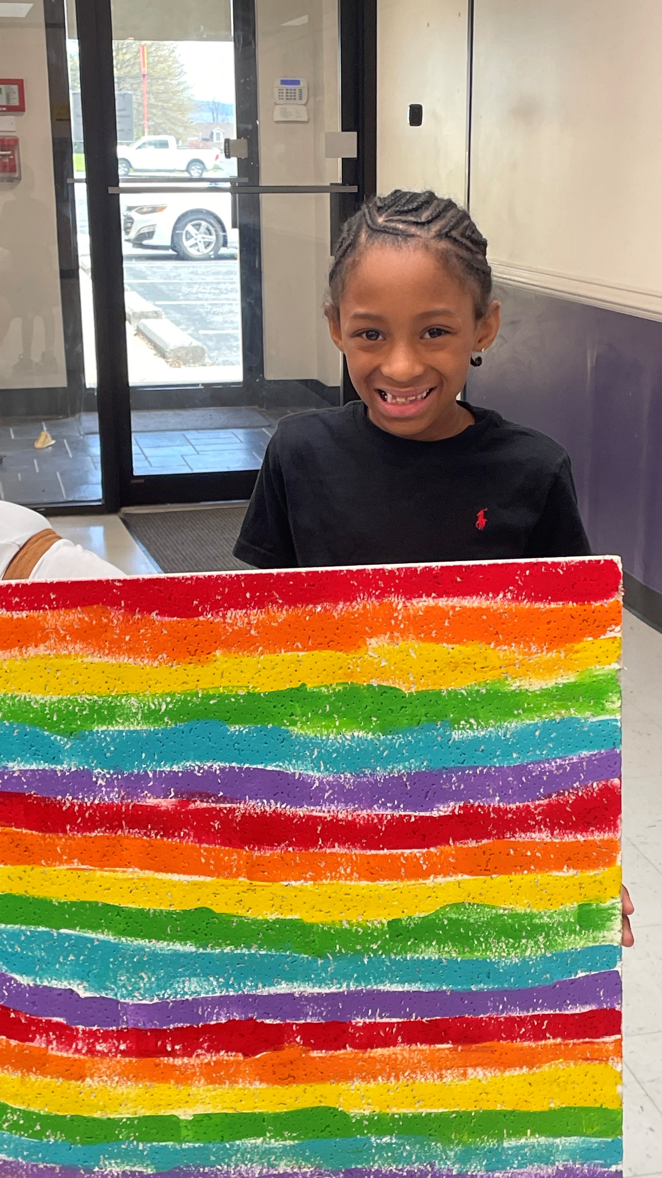 A child holds a painted ceiling tile