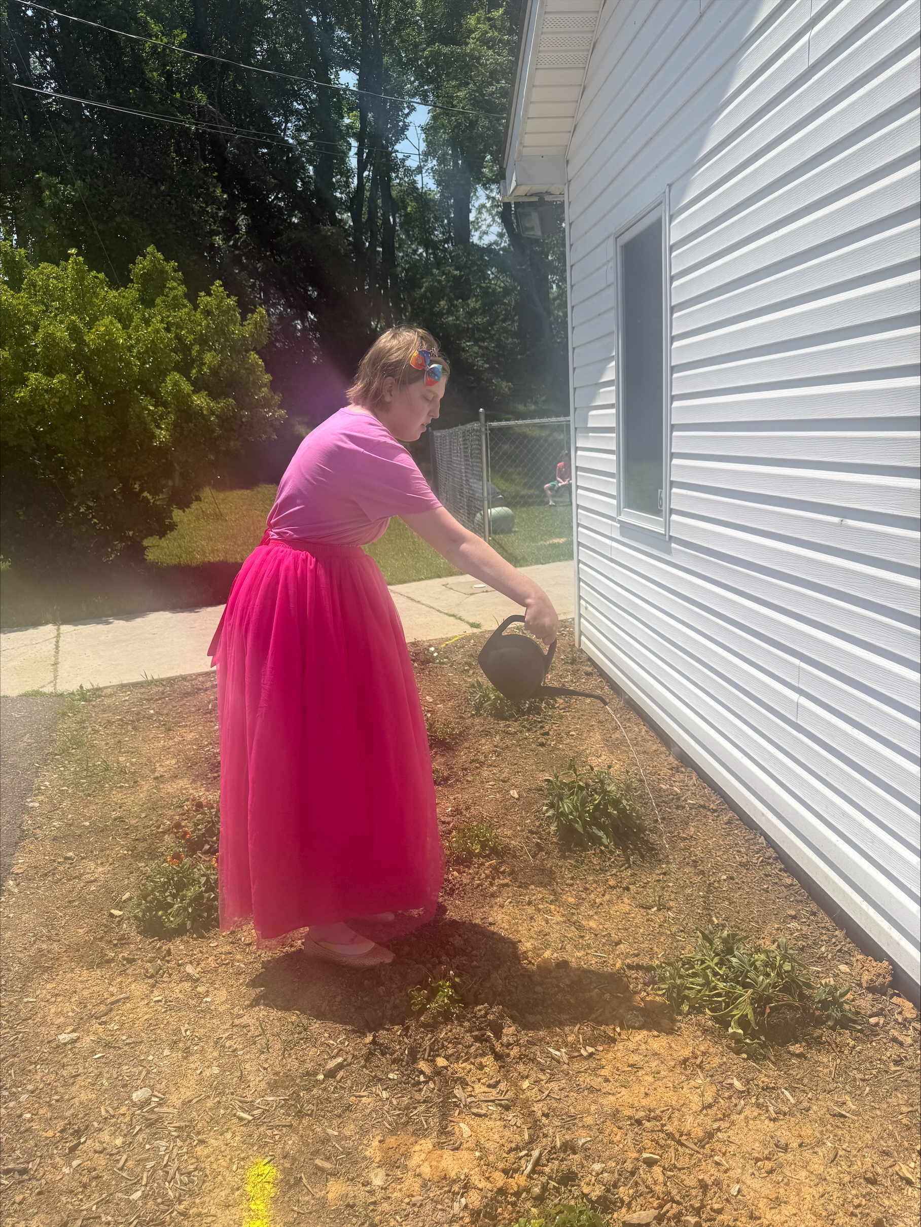 Kaylee dressed as a princess waters a plant