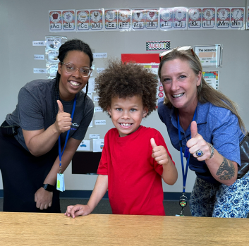 Two teachers and a student give the camera a thumbs up