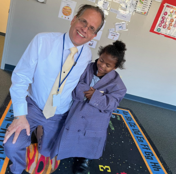 Mr. Wray smiles with Traviar in the classroom