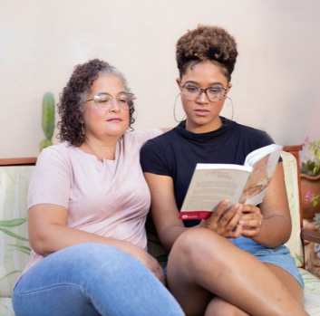 A mother and teen daughter look at a book together