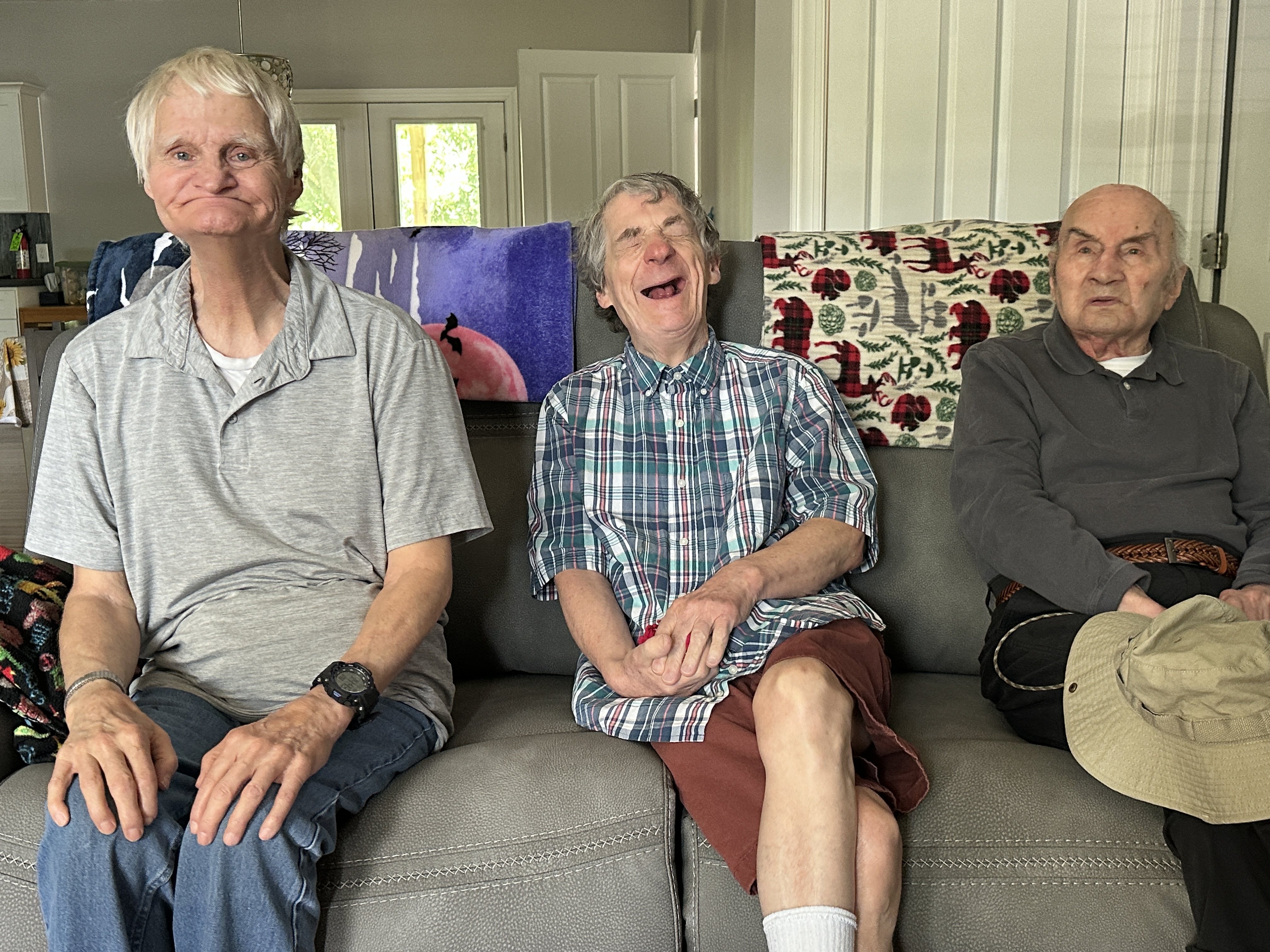 Ronnie, Ed, and Charles smile from the couch of their new home