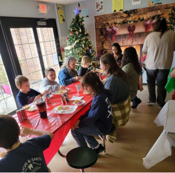 Students sit around a decorated table eating a meal