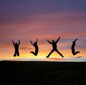 Silhouettes of three teens jumping in front of a sunset sky 