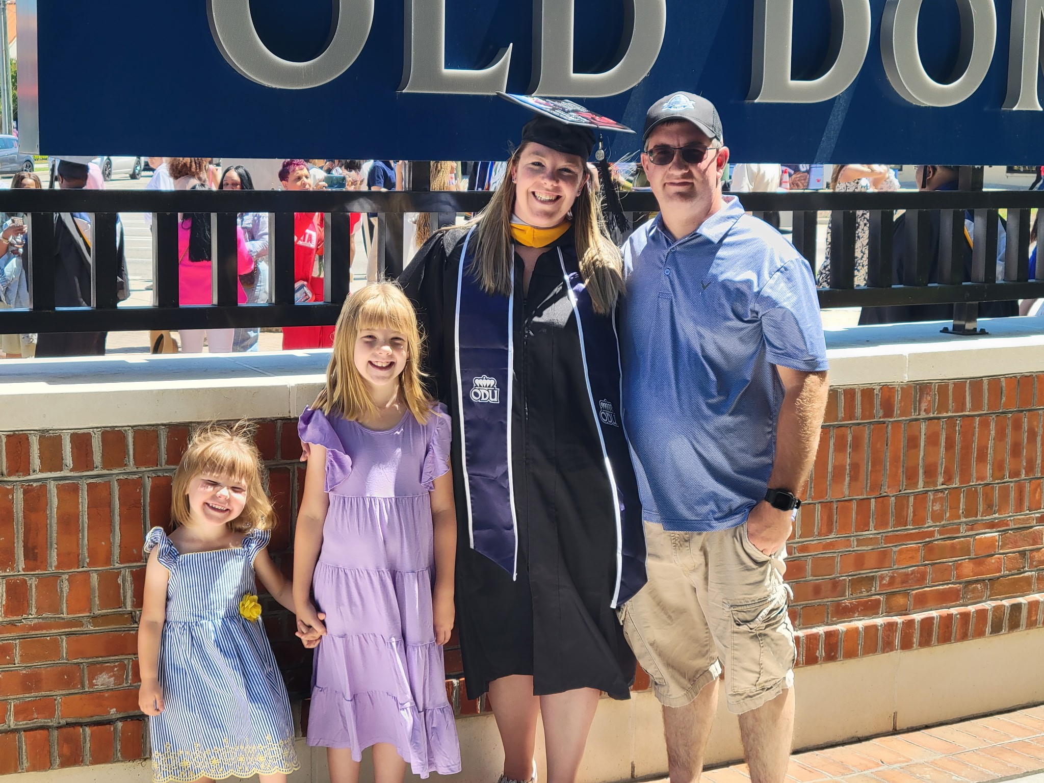 Stephanie stands with her family in her cap and gown