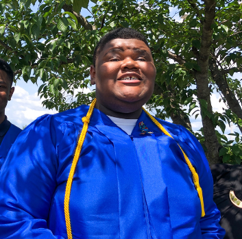 Urius smiles at the camera in his graduation gown