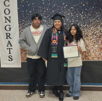 Karina stands in her graduation gown with her children