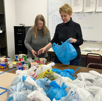 Two volunteers fill lunch bags for students