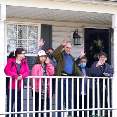 A group of Stonebrooke residents wave at the camera from their front porch