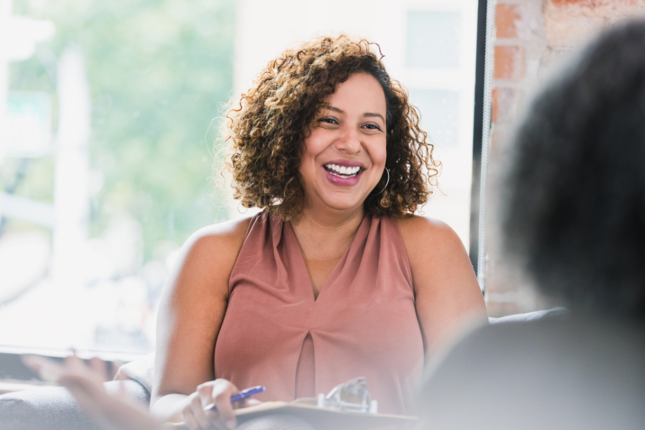 A black woman with curly hair smiles at a client