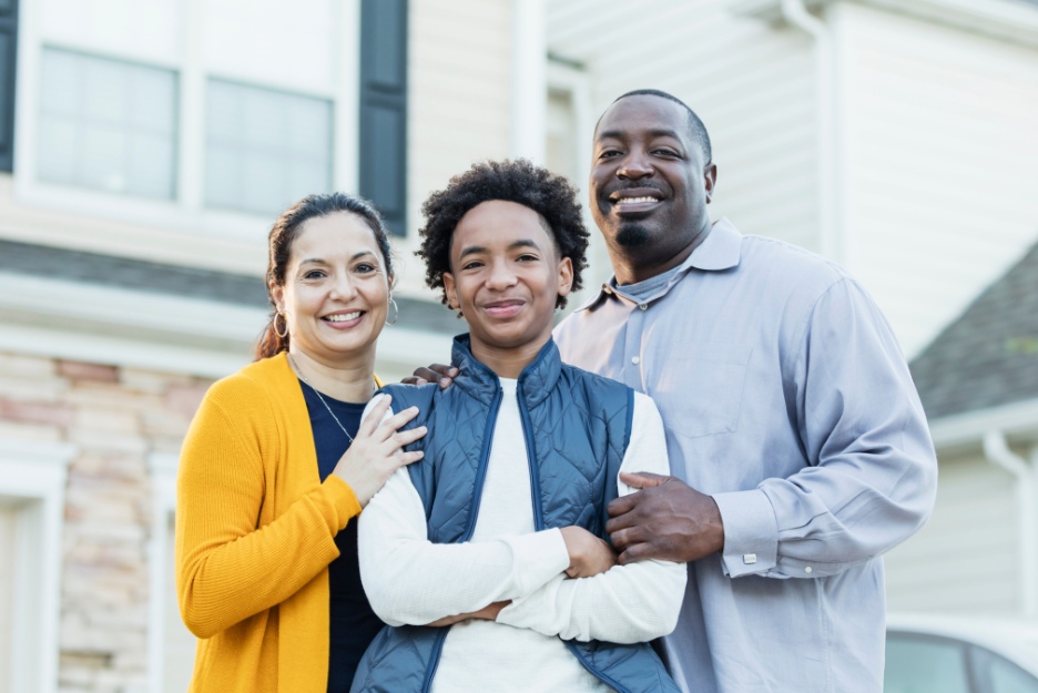 A couple with a teen boy smiles at the camera
