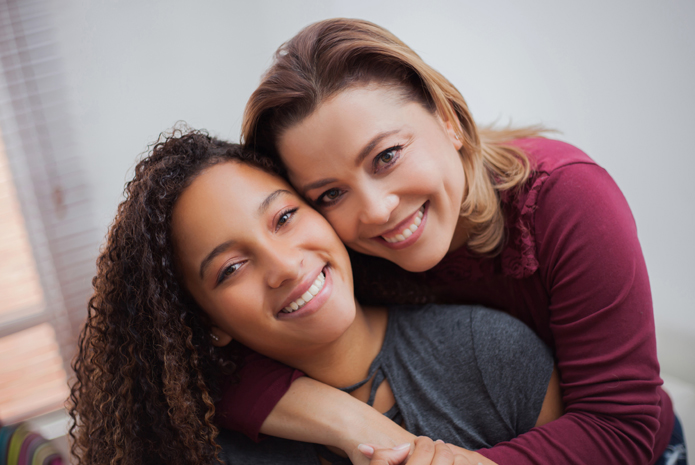 A woman hugs and smiles with a foster youth